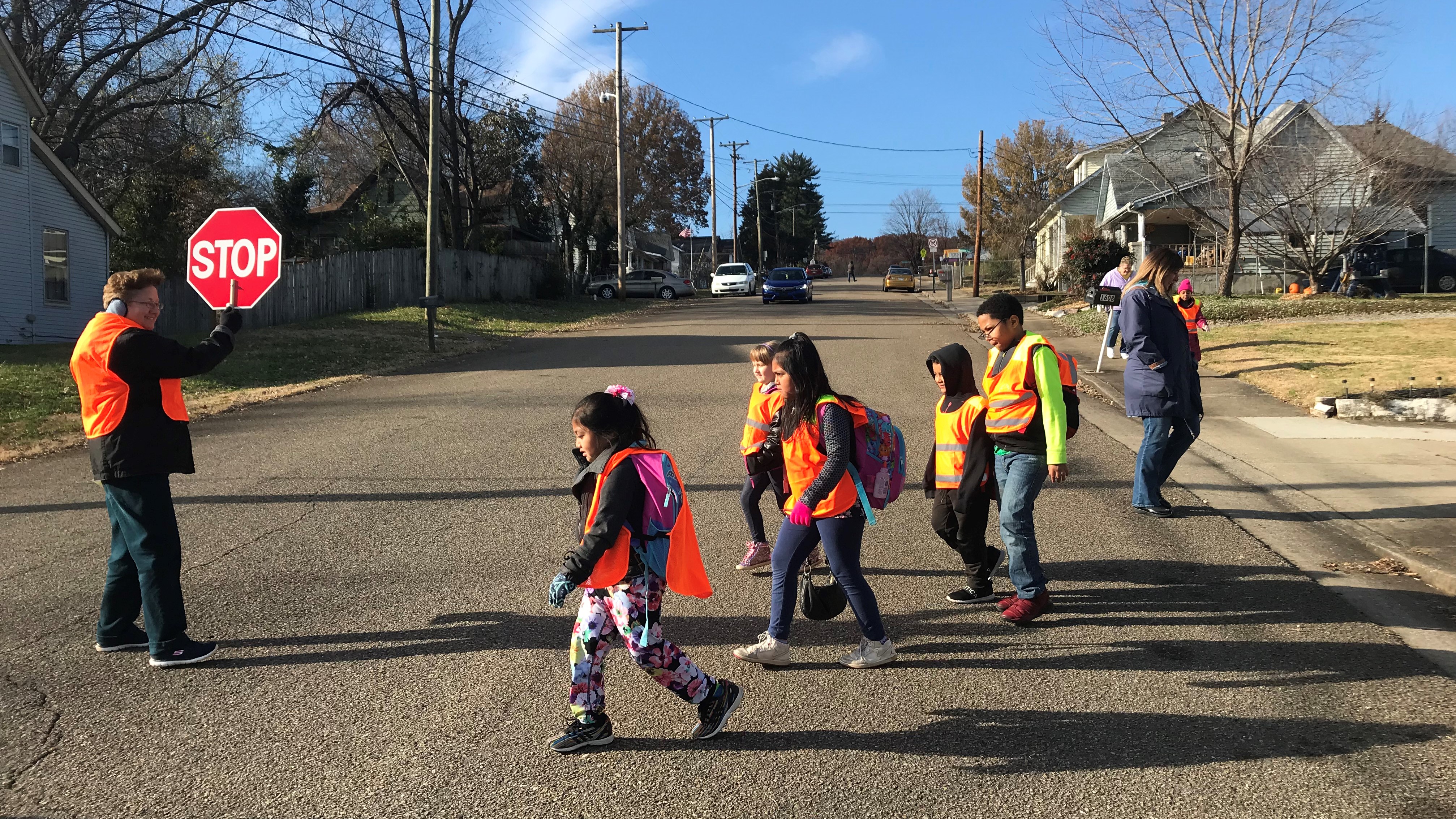 Teaching assistant Cindy Poland holds a stop sign as students from West View Elementary School cross the street. 